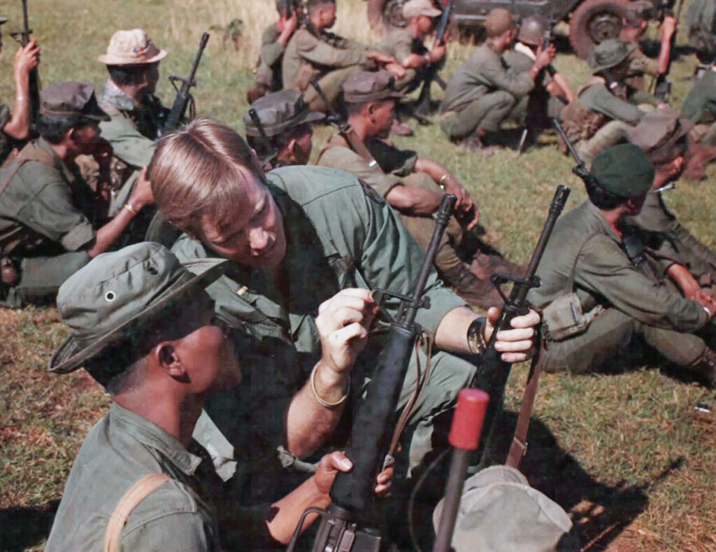Photo of a member of Mobile Advisory Team 36 assisting a Regional Force soldier to adjust the front sight of his M-16 rifle, October 1969 1LT Richard Mooney, a member of the MACV Mobile Advisory Team 36, assists a Regional Force soldier to adjust the front sight of his M-16 rifle.