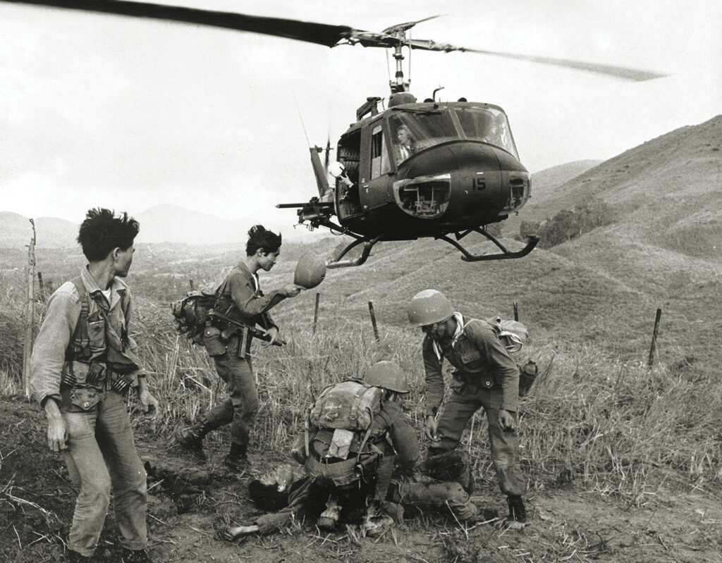 Photo of a helicopter waiting to pick up a wounded South Vietnamese soldier wounded by communist fire. November 1965, Hiep Duc, South Vietnam.