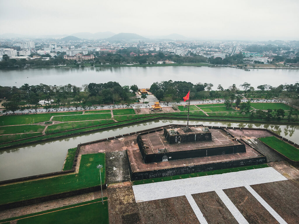 Photo of the Vietnam flag, waving on top of the stage, in front of the Imperial Palace in Heu, Vietnam. Aerial shot.