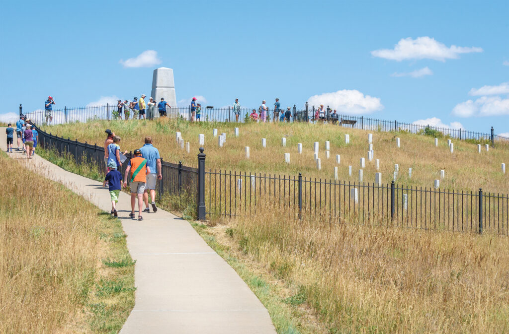 Photo of Little Bighorn Battlefield National Monument, MONTANA, USA - JULY 18, 2017: Tourists visiting Little Bighorn Last Stand monument obelisk and Last Stand Hill grave yard.