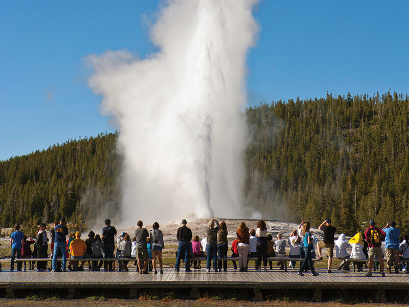 Photo of tourists watching Old Faithful, Yellowstone National Park.