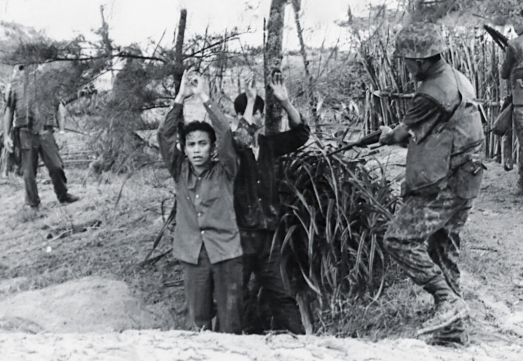 Photo of a ROK Marine (right) takes two Viet Cong insurgents prisoner as they emerge from an underground hiding place.