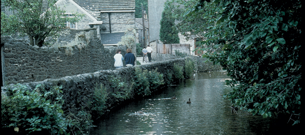 Visitors stroll down the pretty riverside walk from the Peak Cavern to the village of Castelton.