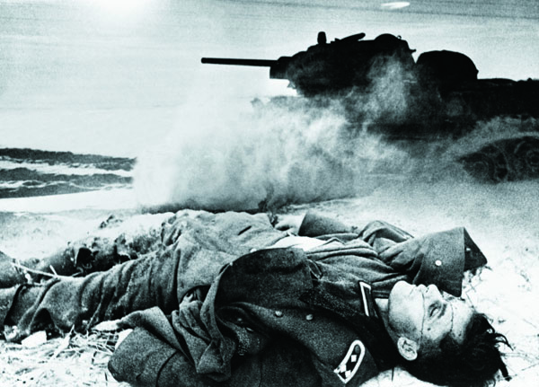 A Soviet T-34/76 tank crosses a snow-covered wasteland near the corpse of a German soldier in 1942, portending an end to the German way of war. [Photo by Slava Katamidze Collection/Getty Images]