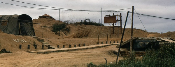 Schiff's basketball court at Cam Lo is flanked by his buried hooch/clinic at right, his supply tent at left and a mess tent in the distance. On Feb. 4, during an afternoon basketball game, an incoming 122mm rocket hit the basketball court seconds after the men had scattered.