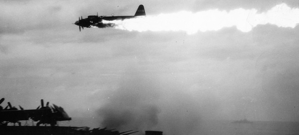 A kamikaze pilot flies over a U.S. carrier in his burning plane. National Archives.
