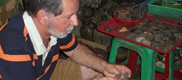 Robert Maves, forensic anthropologist with Joint POW/MIA Accounting Command (JPAC), sifts through a pile of old dog tags in a Ho Chi Minh City shop in 2008, looking for clues about the authenticity of dog tags being hawked in Vietnam. (Courtesy of Robert Mann)
