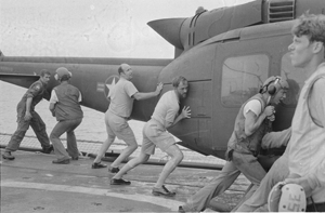 In a scene playing out across the Seventh Fleet, Commander Jacobs (third from left) and Kirk crewmen shove a Huey overboard to make room for more aircraft seeking refuge on April 30. (Photo courtesy of Craig Compiano)