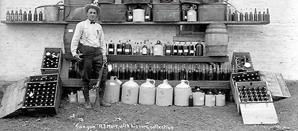 Two-Gun Hart became a Prohibition agent in 1920, keeping his family roots a deep secret. Here he poses with confiscated alcohol. (State Historical Society of North Dakota, 1952-0088)