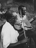 Wilson "Stavin' Chain" Jones and an unidentified fiddler perform "Batson" in 1934. The song was based on a real-life 1902 murder in Welsh, La. (Library of Congress)