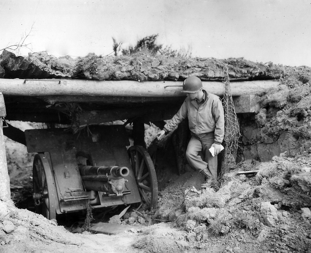 A 1st Infantry Division officer examines a German-manned French 75mm cannon overlooking Easy Red—typical of a variety of captured French weapons that the Germans pressed into service to defend the “West Wall” while freeing up their latest and most powerful weaponry for deployment against the Soviet army. Elements of the German 352nd Infantry Division were stretched across Omaha to face the Americans all along Omaha Beach, but their fortifications, stiffened in recent months by General Erwin Rommel, proved to be a formidable combat multiplier. (National Archives)